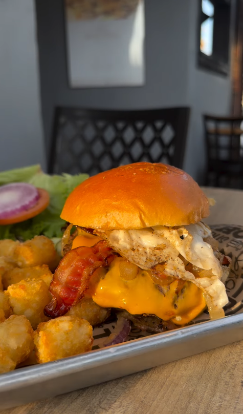 Bacon cheeseburger topped with a fried egg, served with tater tots